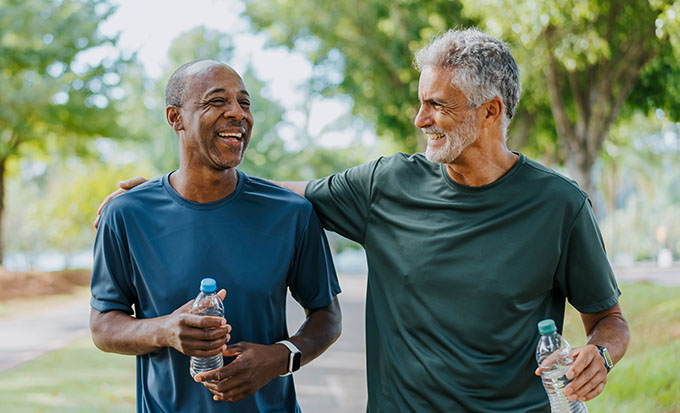 Two mature men holding water bottles outdoors