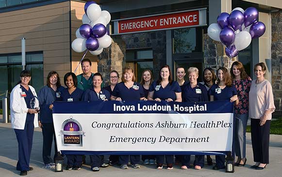 nurses in front of emergency room smiling with congratulations sign