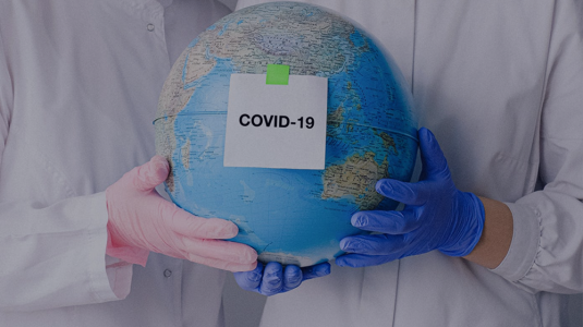 gloved hands holding a globe with COVID-19 label on it