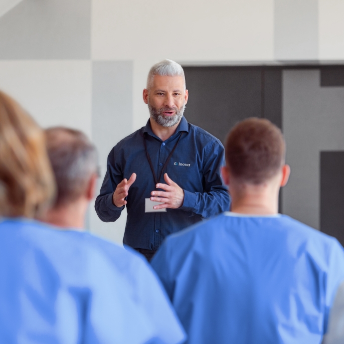 a man wearing professional clothing speaking in front of a room of medical staff